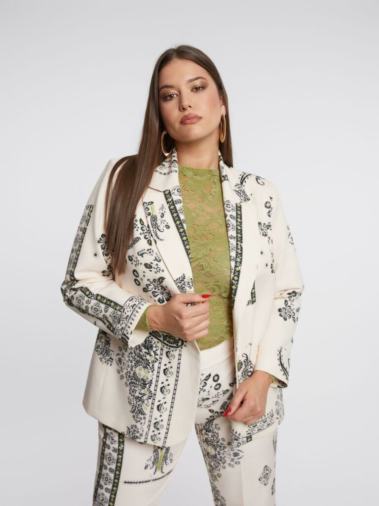 Plus size μοντέλο ποζάρει με εκρού σακάκι με μοτίβο λαχούρι.